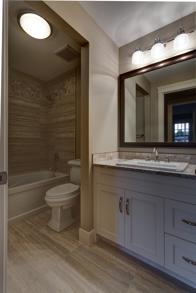 Exempel på ett mellanstort klassiskt en-suite badrum, med ett nedsänkt handfat, luckor med infälld panel, vita skåp, granitbänkskiva, ett hörnbadkar, en dusch/badkar-kombination, en toalettstol med hel cisternkåpa, beige kakel och beige väggar