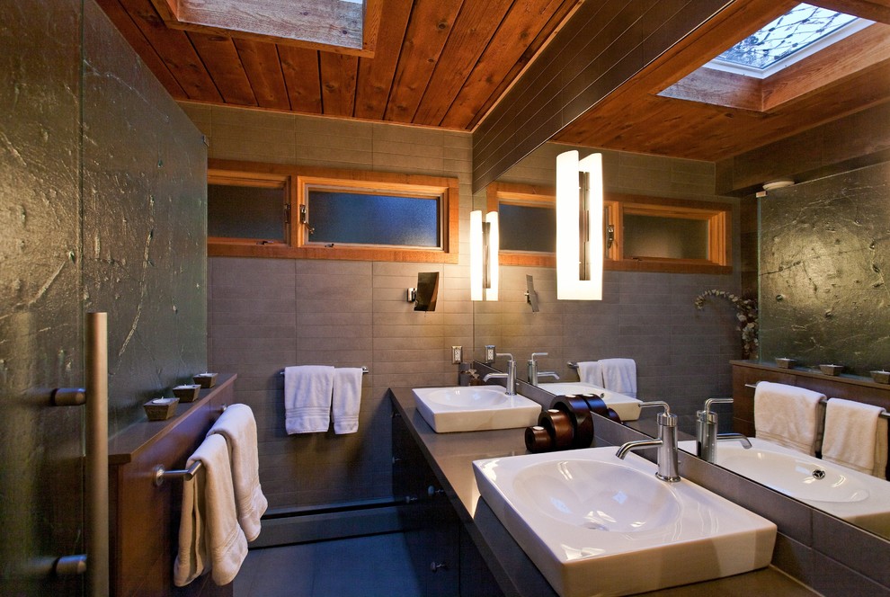 Idée de décoration pour une salle de bain vintage en bois foncé avec une vasque, un placard à porte plane, un plan de toilette en quartz modifié, un carrelage gris, des carreaux de porcelaine, un sol en carrelage de porcelaine et une fenêtre.