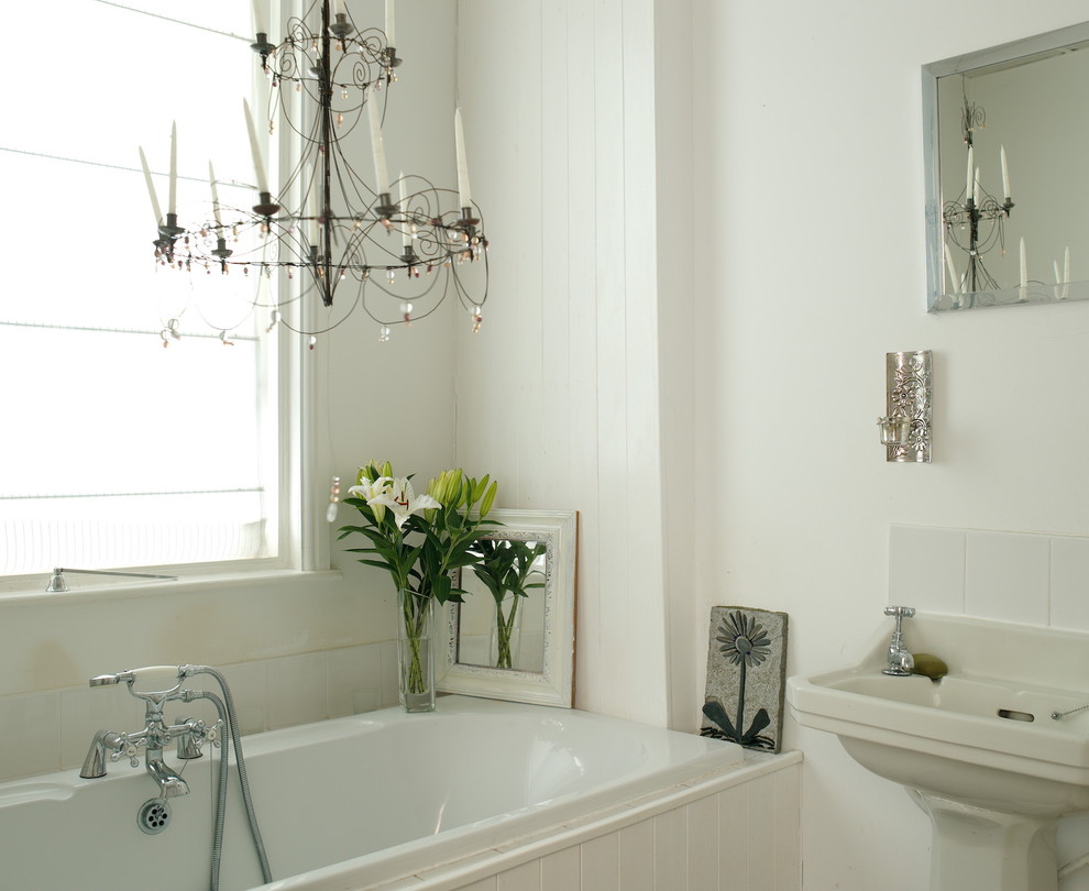 This is an example of a farmhouse bathroom in Other with a built-in bath, white tiles, white walls and a pedestal sink.