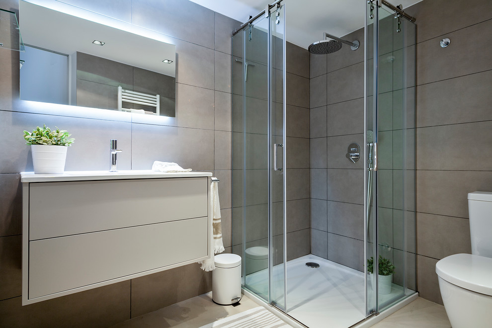 Ejemplo de cuarto de baño actual de tamaño medio con armarios con paneles lisos, puertas de armario beige, ducha esquinera, sanitario de dos piezas, paredes beige, aseo y ducha y lavabo integrado