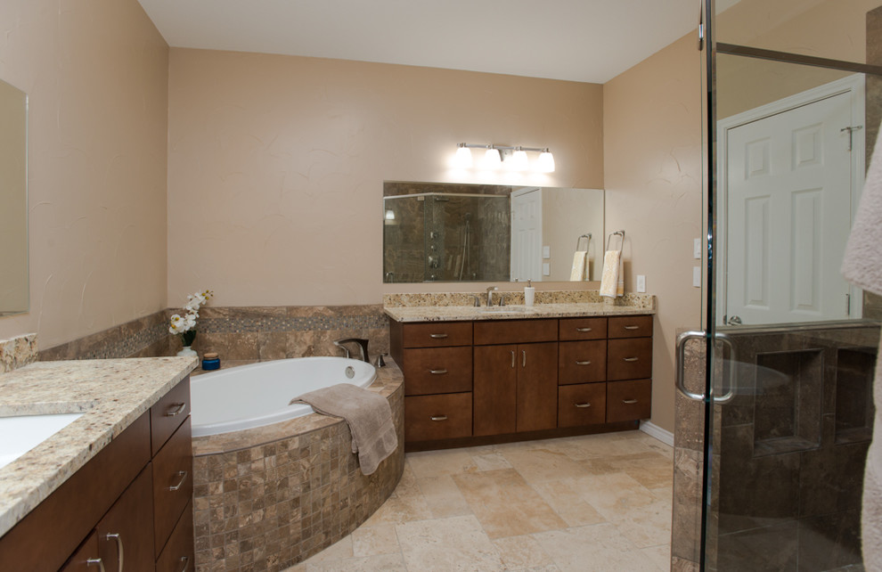 This is an example of a medium sized classic ensuite bathroom in Dallas with flat-panel cabinets, medium wood cabinets, a built-in bath, a corner shower, a two-piece toilet, brown tiles, porcelain tiles, beige walls, travertine flooring, a submerged sink, granite worktops, beige floors, a hinged door and multi-coloured worktops.