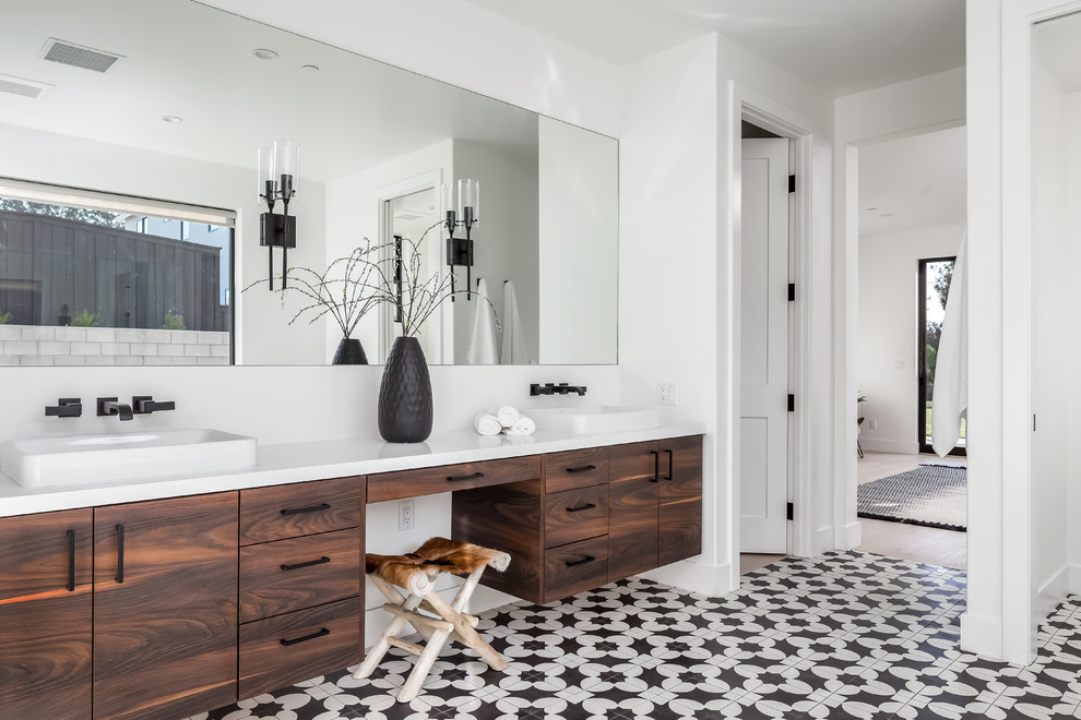 サンディエゴにあるコンテンポラリースタイルのおしゃれな浴室 (フラットパネル扉のキャビネット、濃色木目調キャビネット、白い壁、オーバーカウンターシンク、マルチカラーの床、白い洗面カウンター) の写真