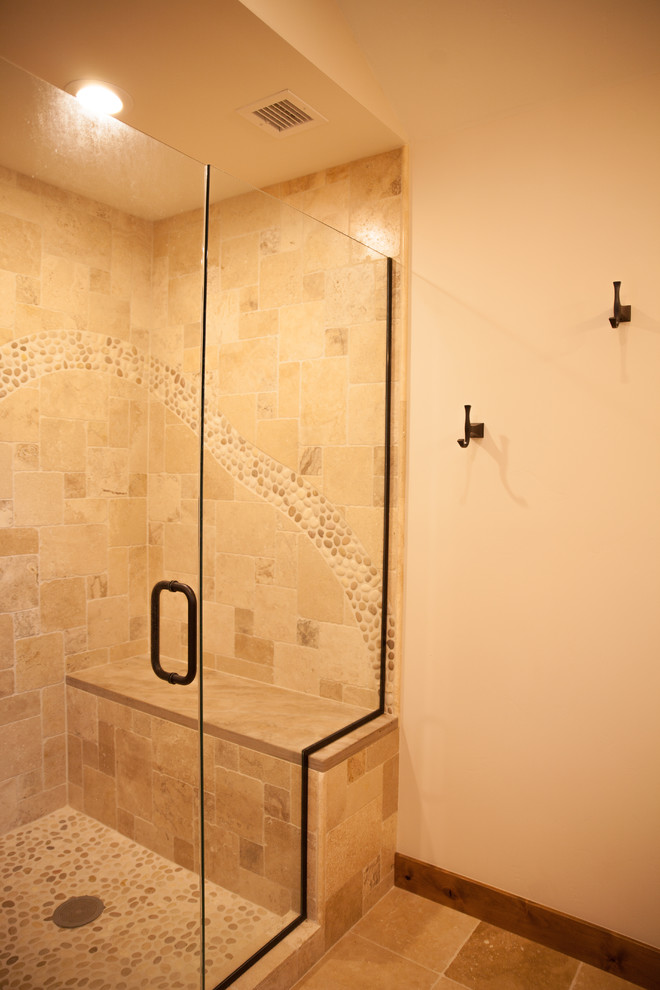 Cette image montre une douche en alcôve principale chalet en bois foncé de taille moyenne avec un placard à porte shaker, une baignoire posée, un carrelage beige, un carrelage de pierre, un mur beige, un sol en carrelage de porcelaine, un lavabo encastré, un plan de toilette en marbre, un sol beige et une cabine de douche à porte battante.
