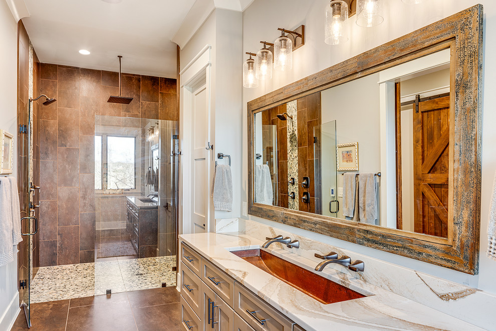 Mid-sized mountain style master brown tile brown floor alcove shower photo in Other with recessed-panel cabinets, beige cabinets, a one-piece toilet, gray walls, an undermount sink, a hinged shower door and multicolored countertops