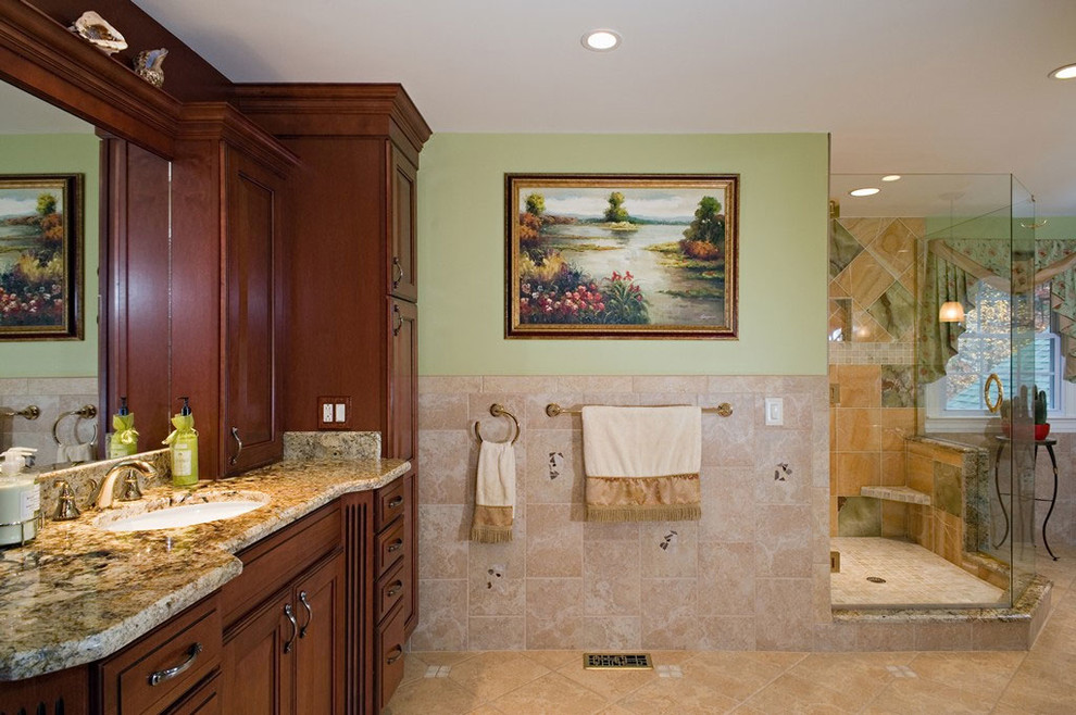 Ejemplo de cuarto de baño tradicional con armarios con paneles con relieve, puertas de armario de madera en tonos medios, encimera de granito, baldosas y/o azulejos verdes y ducha esquinera