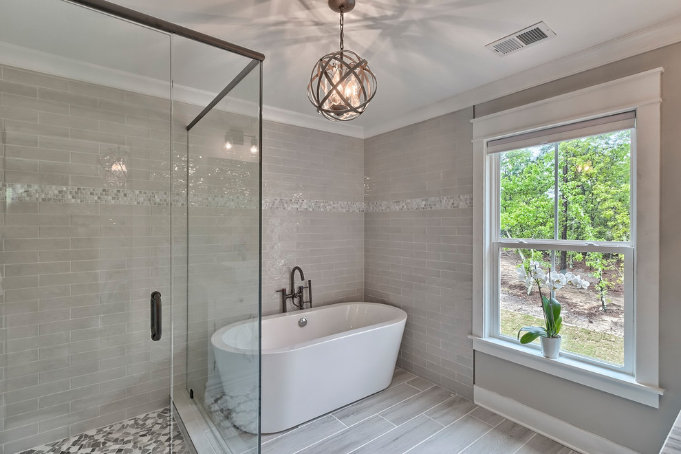 Inredning av ett modernt mellanstort grå grått en-suite badrum, med möbel-liknande, bruna skåp, ett fristående badkar, en öppen dusch, en toalettstol med hel cisternkåpa, grå kakel, tunnelbanekakel, grå väggar, klinkergolv i porslin, ett integrerad handfat, marmorbänkskiva, grått golv och dusch med gångjärnsdörr
