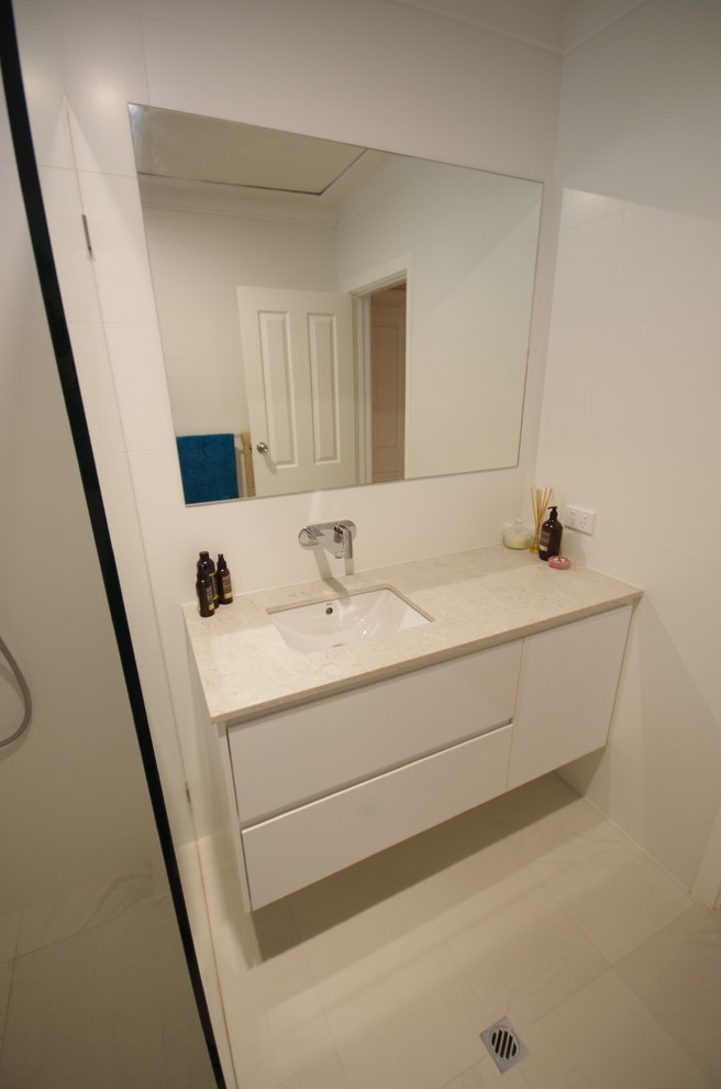 Inredning av ett modernt vit vitt en-suite badrum, med möbel-liknande, vita skåp, en öppen dusch, vit kakel, porslinskakel, vita väggar, klinkergolv i porslin, ett undermonterad handfat, bänkskiva i kvarts, gult golv och med dusch som är öppen