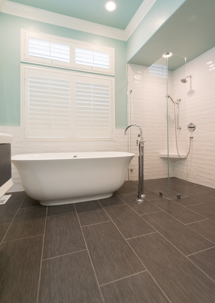 Cette image montre une grande salle de bain principale design avec une baignoire indépendante, une douche d'angle, un carrelage blanc, des carreaux de céramique, un mur bleu, un sol en carrelage de céramique, un sol gris et une cabine de douche à porte battante.