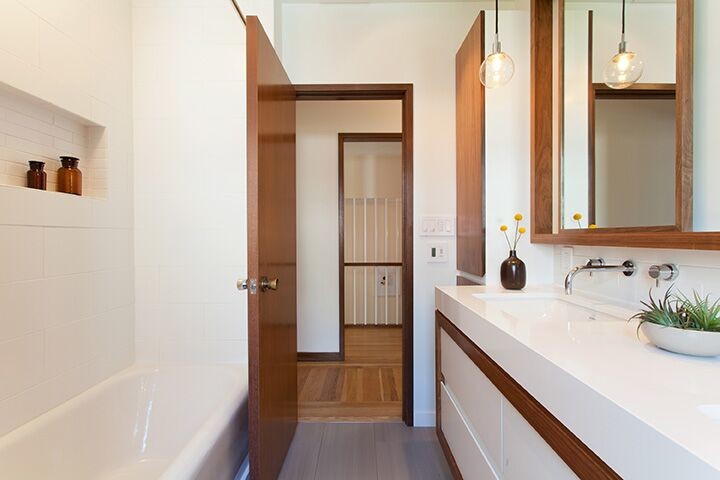 Idéer för mellanstora funkis badrum, med släta luckor, vita skåp, ett badkar i en alkov, en dusch/badkar-kombination, vit kakel, vita väggar, ett undermonterad handfat, klinkergolv i porslin och brunt golv
