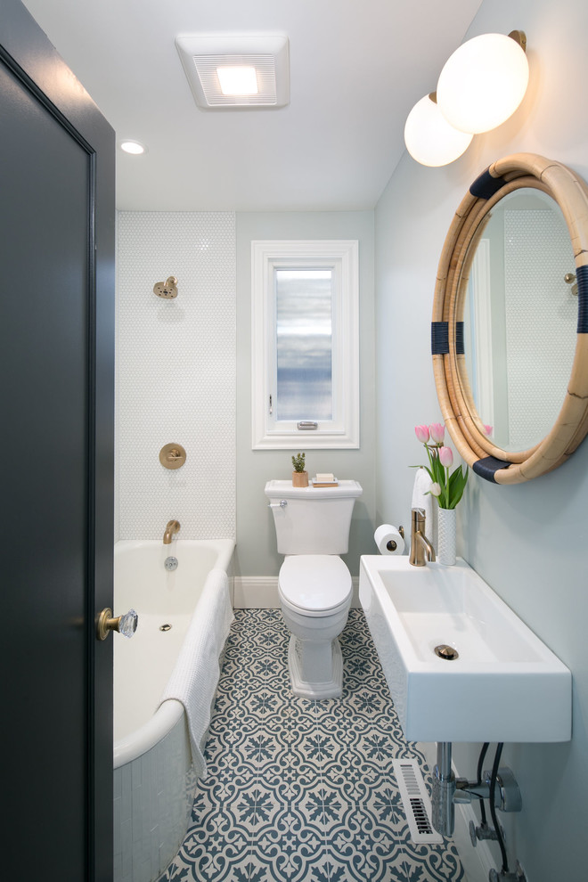 Foto på ett litet vintage badrum för barn, med ett hörnbadkar, en dusch/badkar-kombination, en toalettstol med separat cisternkåpa, vit kakel, porslinskakel, blå väggar, mosaikgolv, ett väggmonterat handfat och blått golv