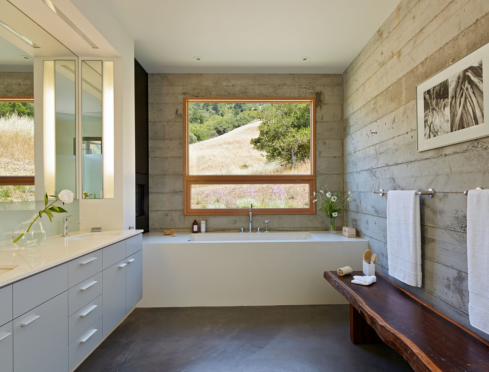 Example of a large minimalist master white tile and porcelain tile concrete floor walk-in shower design in San Francisco with flat-panel cabinets, blue cabinets, an undermount tub, a two-piece toilet, gray walls, an undermount sink and quartz countertops