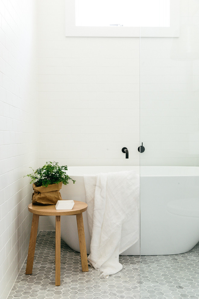 Small danish white tile mosaic tile floor freestanding bathtub photo in Sydney with white walls