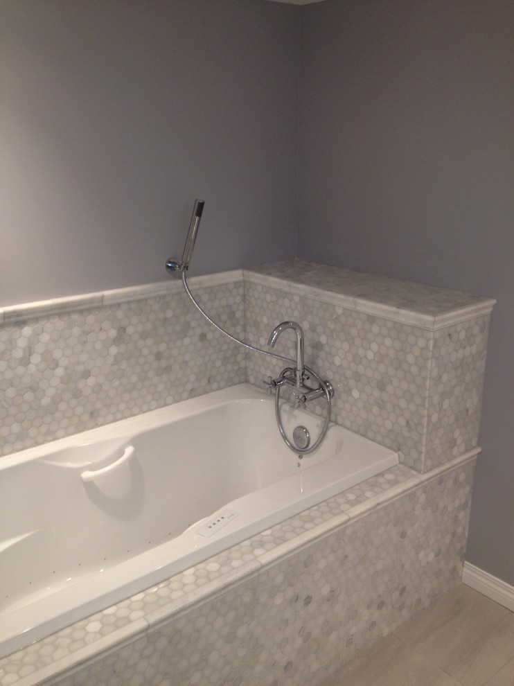 Modelo de cuarto de baño de estilo americano con bañera encastrada, baldosas y/o azulejos grises, baldosas y/o azulejos de porcelana, paredes grises, suelo de baldosas de porcelana y aseo y ducha