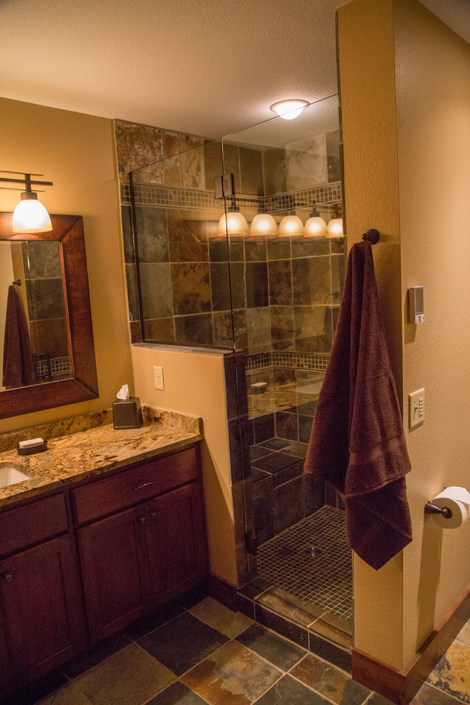 Bild på ett rustikt badrum med dusch, med luckor med infälld panel, skåp i slitet trä, en hörndusch, en toalettstol med hel cisternkåpa, flerfärgad kakel, glasskiva, skiffergolv, ett undermonterad handfat och granitbänkskiva