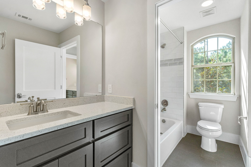Inspiration for a traditional family bathroom in Houston with shaker cabinets, brown cabinets, an alcove bath, an alcove shower, a one-piece toilet, white tiles, ceramic tiles, beige walls, ceramic flooring, a submerged sink, engineered stone worktops, grey floors, a shower curtain, white worktops, a single sink and a built in vanity unit.