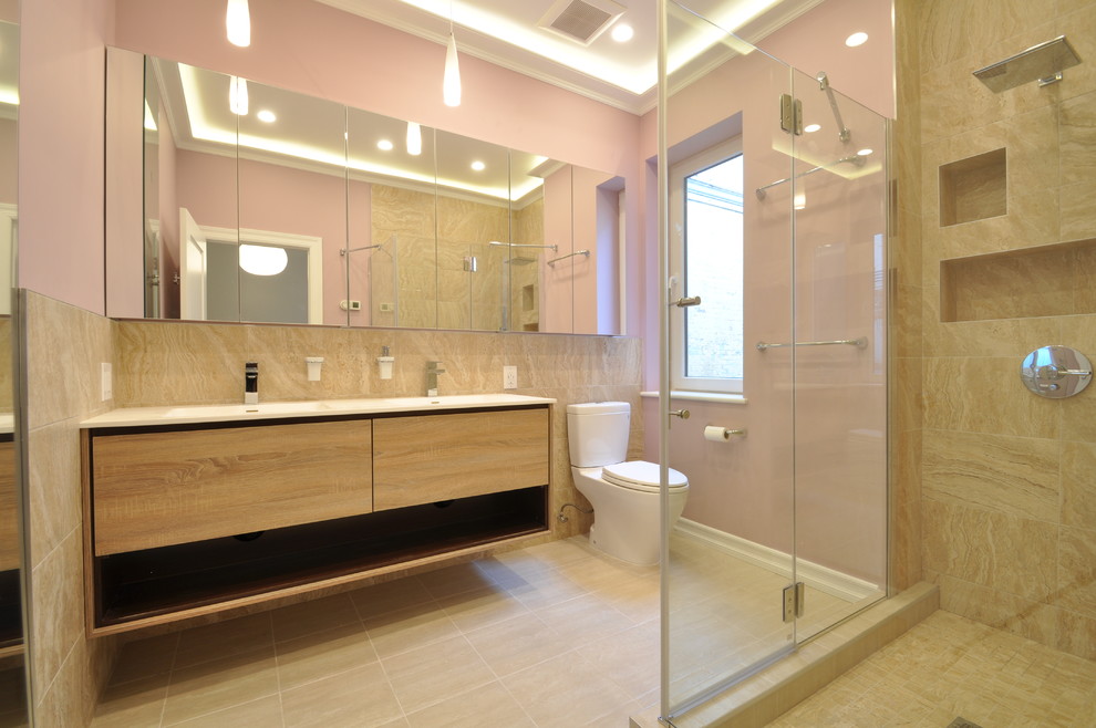 Corner shower - mid-sized contemporary master beige tile and stone tile ceramic tile corner shower idea in New York with flat-panel cabinets, light wood cabinets, a two-piece toilet, pink walls, an undermount sink and solid surface countertops