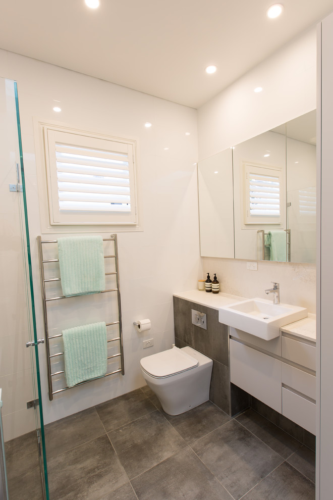 Modelo de cuarto de baño principal moderno de tamaño medio con bañera encastrada, sanitario de pared, encimera de cuarzo compacto y encimeras blancas
