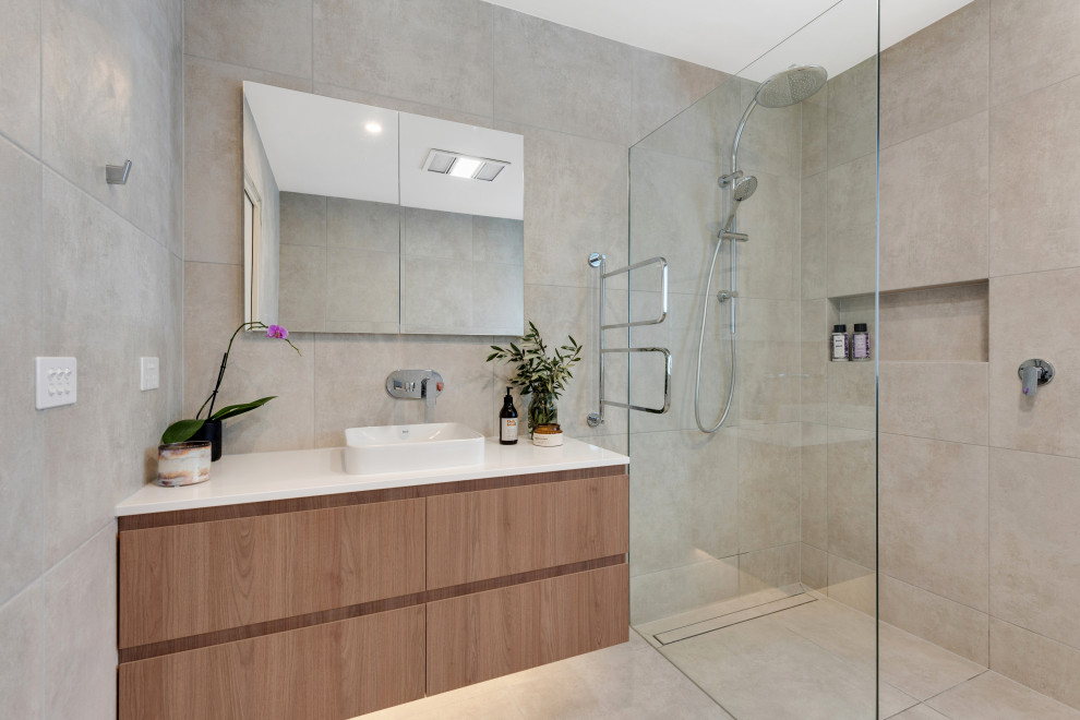 Bild på ett funkis vit vitt badrum med dusch, med släta luckor, skåp i mellenmörkt trä, en kantlös dusch, beige kakel, ett fristående handfat, beiget golv och med dusch som är öppen