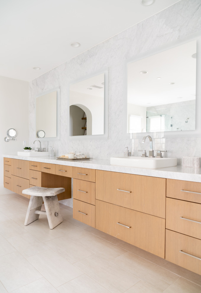 Photo of a coastal bathroom in Orange County with flat-panel cabinets, light wood cabinets, white tiles, white walls, a built-in sink, white floors, white worktops, double sinks and a built in vanity unit.