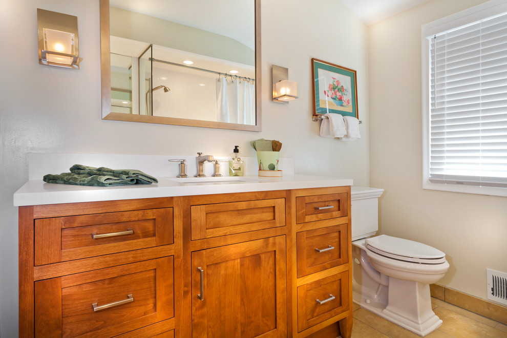Inspiration for a mid-sized transitional master white tile and porcelain tile travertine floor bathroom remodel in Minneapolis with an undermount sink, recessed-panel cabinets, medium tone wood cabinets, solid surface countertops, a two-piece toilet and white walls