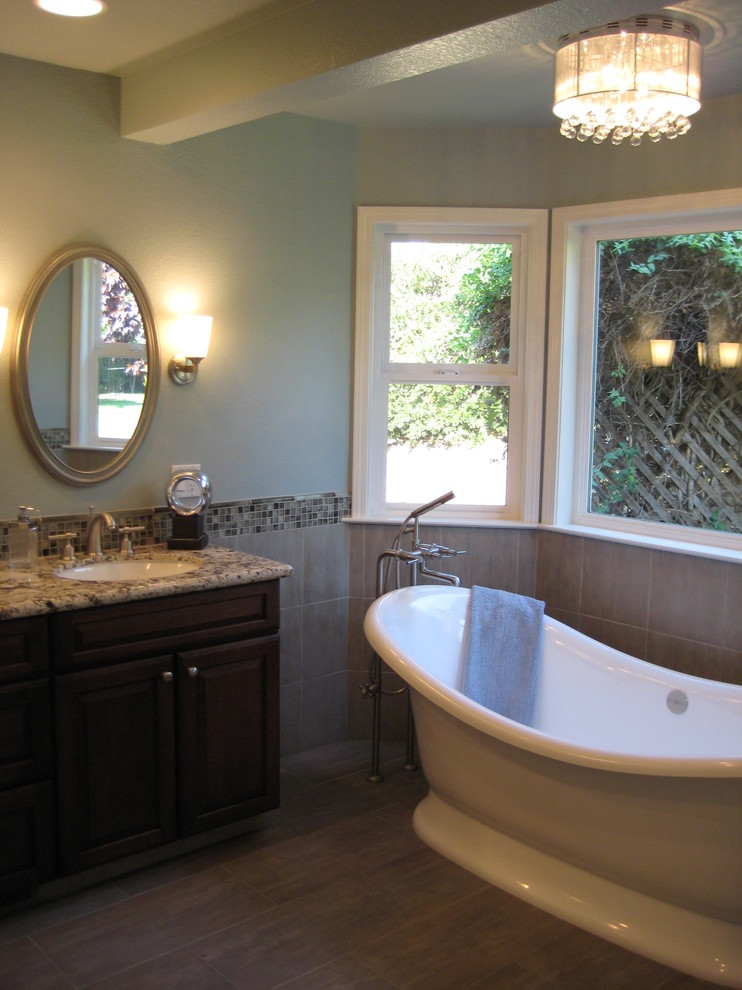 Bild på ett mellanstort vintage en-suite badrum, med ett undermonterad handfat, luckor med upphöjd panel, skåp i mörkt trä, granitbänkskiva, ett fristående badkar, en dusch i en alkov, en toalettstol med separat cisternkåpa, brun kakel, blå väggar och klinkergolv i porslin