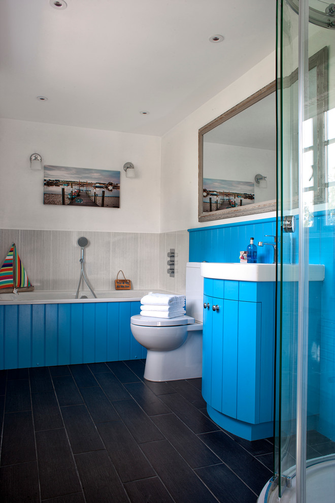 Idee per una stanza da bagno costiera con ante blu, vasca da incasso, doccia ad angolo, WC a due pezzi, piastrelle grigie, pareti bianche, lavabo a consolle e ante lisce