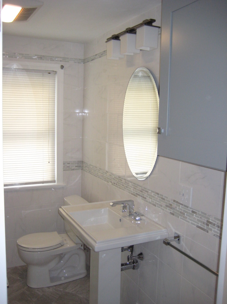 Medium sized traditional shower room bathroom in Boston with flat-panel cabinets, grey cabinets, an alcove shower, a two-piece toilet, white tiles, white walls, porcelain flooring, a pedestal sink, grey floors, a sliding door and marble tiles.