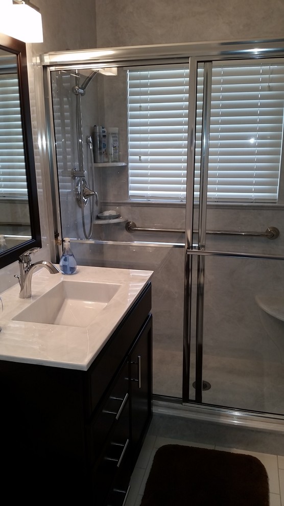 Idéer för att renovera ett mellanstort funkis badrum med dusch, med ett integrerad handfat, skåp i mörkt trä, bänkskiva i akrylsten, en dusch i en alkov, en toalettstol med separat cisternkåpa, vita väggar, klinkergolv i porslin, släta luckor, vitt golv och dusch med skjutdörr