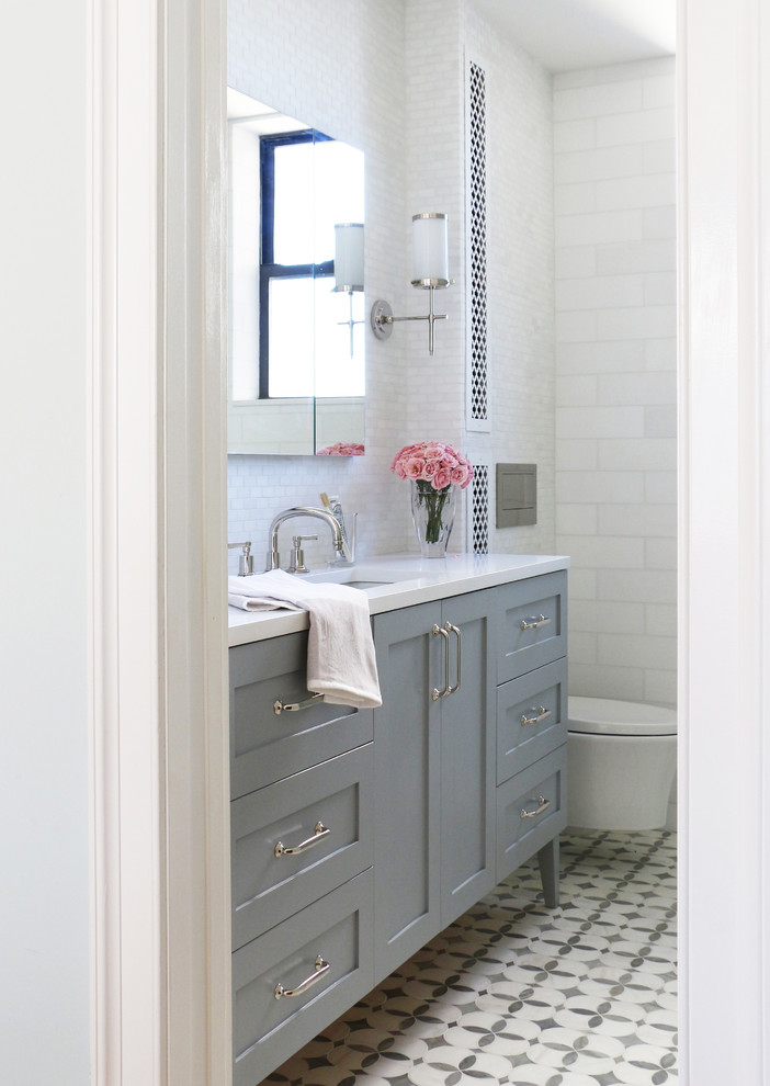 Mid-sized transitional master white tile and marble tile marble floor and gray floor alcove shower photo in Los Angeles with shaker cabinets, gray cabinets, a wall-mount toilet, white walls, an undermount sink, quartz countertops and a hinged shower door