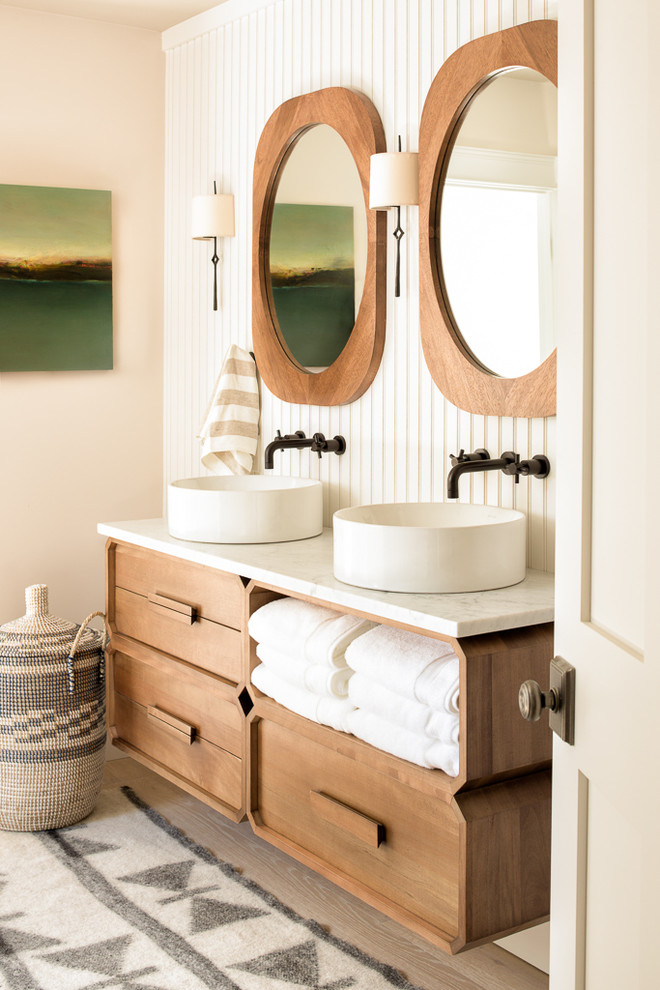 This is an example of a coastal bathroom in Portland Maine with medium wood cabinets, beige walls, light hardwood flooring, a vessel sink and beige floors.