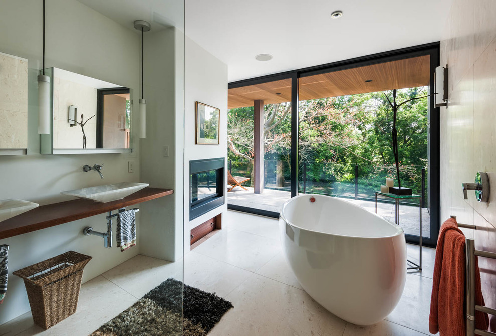 Idée de décoration pour une grande salle de bain principale design avec une baignoire indépendante, un mur gris, une vasque et un plan de toilette en bois.