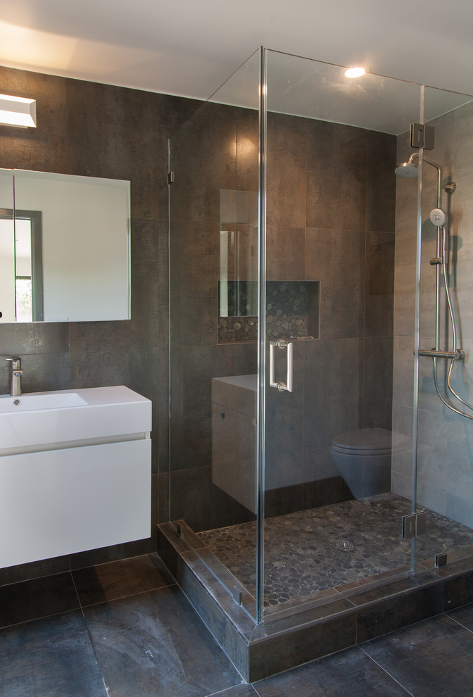 Inredning av ett modernt mellanstort badrum med dusch, med släta luckor, vita skåp, bänkskiva i akrylsten, en dusch i en alkov, grå kakel och porslinskakel