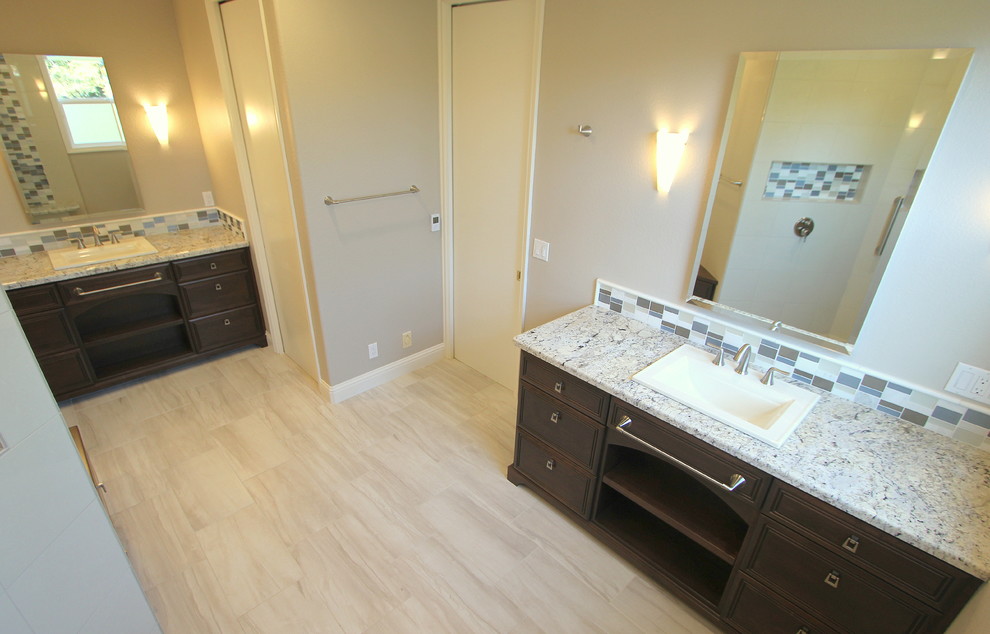 Example of a mid-sized trendy beige tile and porcelain tile porcelain tile corner shower design in Sacramento with a drop-in sink, furniture-like cabinets, dark wood cabinets, granite countertops and beige walls