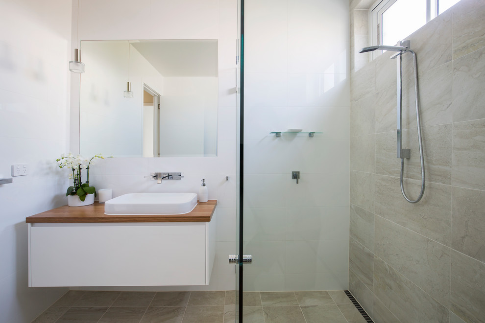 Cette image montre une grande salle de bain nordique avec une douche ouverte, un carrelage multicolore, des carreaux de porcelaine, un plan de toilette en bois et aucune cabine.