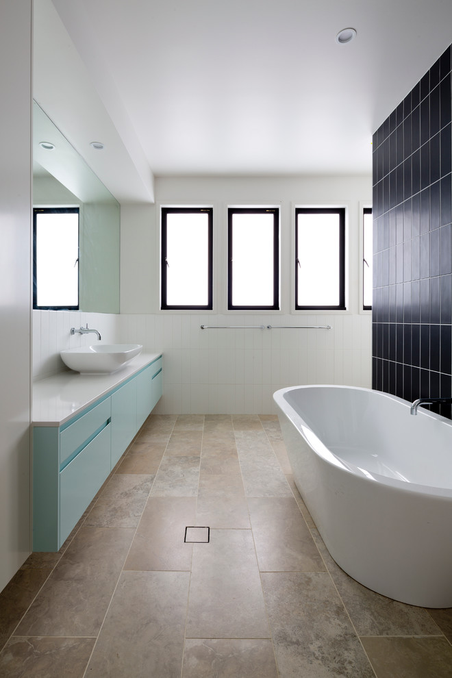 Foto di una stanza da bagno contemporanea con lavabo a bacinella, ante lisce, ante blu, vasca freestanding e piastrelle beige