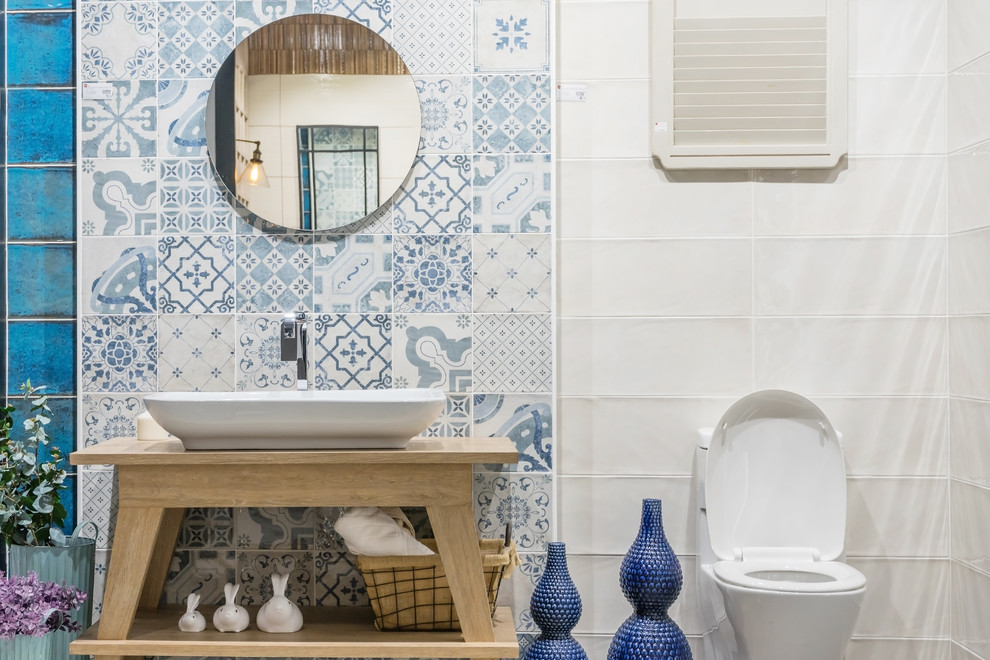 Cette photo montre une salle d'eau méditerranéenne avec WC à poser, un carrelage bleu, un carrelage blanc, une vasque, un plan de toilette en bois et du carrelage bicolore.