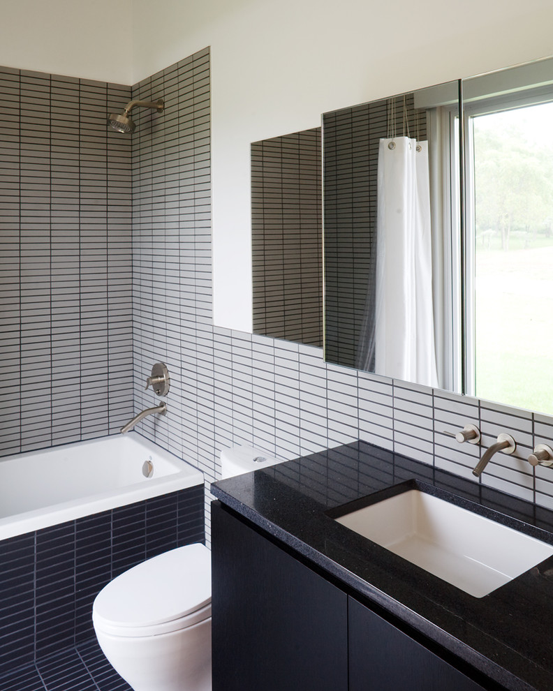 Cette image montre une salle de bain design avec un lavabo encastré, des portes de placard noires et un carrelage gris.