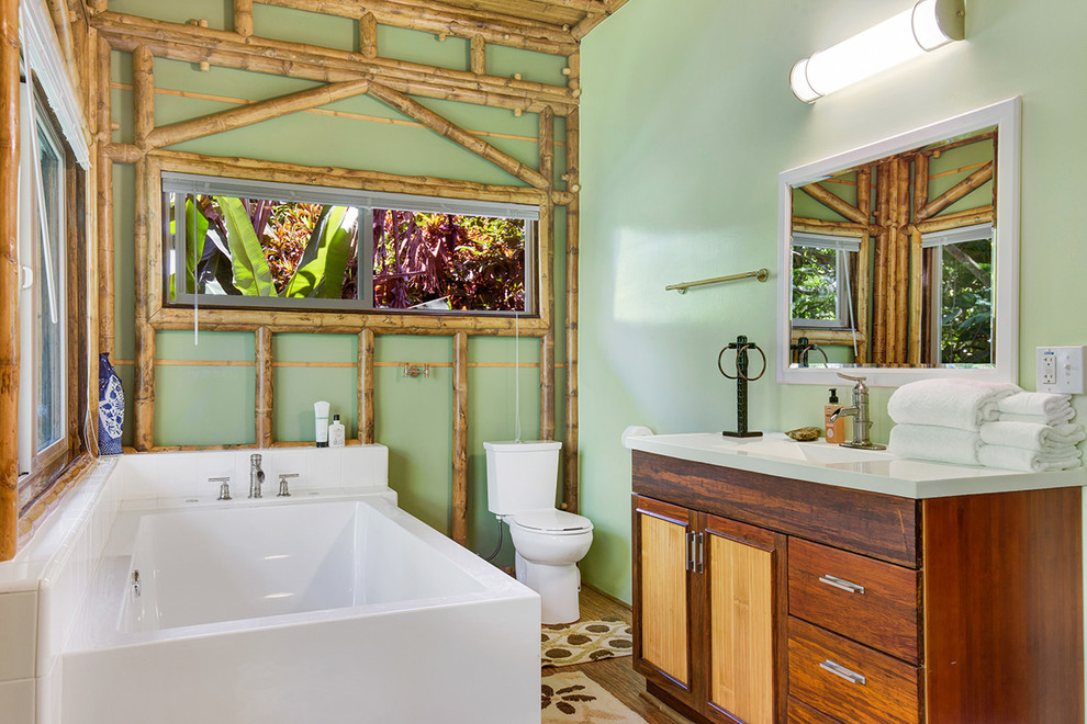 Inredning av ett exotiskt badrum, med ett hörnbadkar, gröna väggar och bambugolv