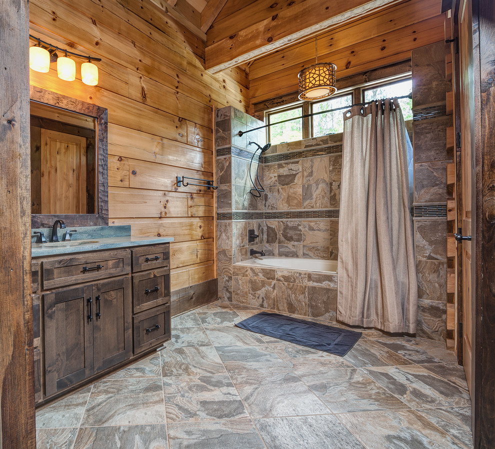 Ejemplo de cuarto de baño rural con lavabo bajoencimera, armarios estilo shaker, puertas de armario de madera en tonos medios, bañera empotrada, combinación de ducha y bañera, baldosas y/o azulejos marrones y encimeras azules