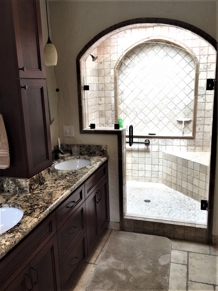 Cette image montre une petite salle de bain traditionnelle en bois foncé avec un placard à porte shaker, une baignoire posée, un carrelage beige, un mur beige, un lavabo intégré, un plan de toilette en granite, un sol beige et une cabine de douche à porte battante.