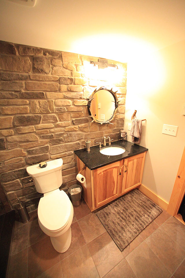 Réalisation d'une salle de bain chalet en bois brun de taille moyenne avec un placard avec porte à panneau surélevé, WC séparés, un carrelage noir, un carrelage marron, un carrelage gris, un carrelage de pierre, un mur gris, un sol en carrelage de céramique, un lavabo encastré et un plan de toilette en granite.