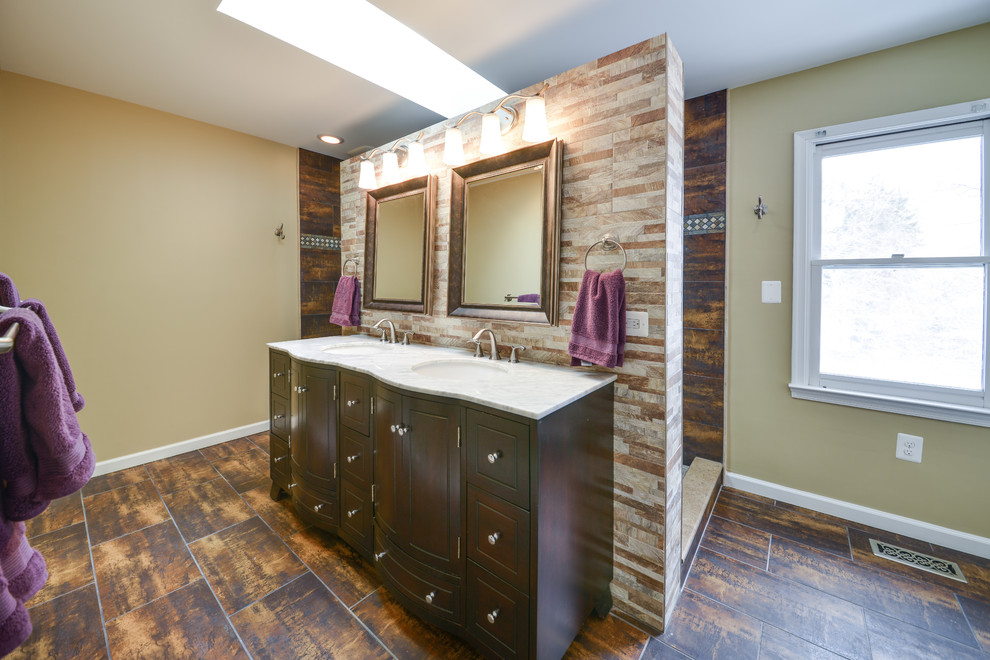 This is an example of a large contemporary ensuite bathroom in DC Metro with beaded cabinets, brown cabinets, a walk-in shower, a two-piece toilet, beige tiles, brown tiles, porcelain tiles, beige walls, porcelain flooring, a submerged sink, brown floors, an open shower, white worktops, an enclosed toilet, double sinks, a freestanding vanity unit and marble worktops.