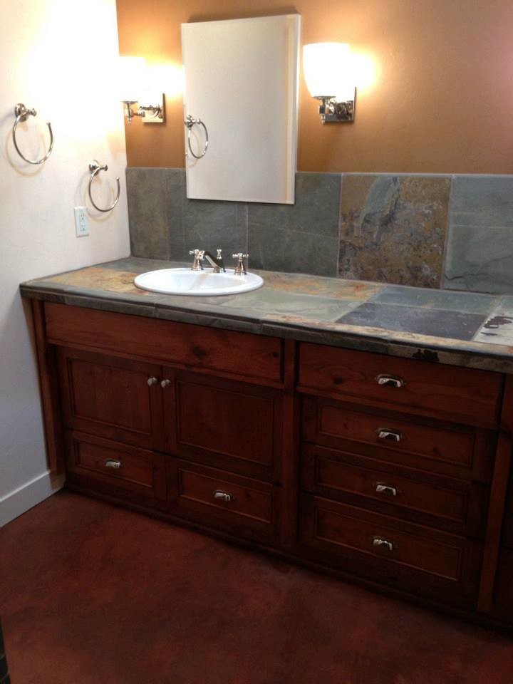 This is an example of a medium sized classic ensuite bathroom in Phoenix with a built-in sink, medium wood cabinets, multi-coloured walls, freestanding cabinets, concrete flooring, a two-piece toilet, grey tiles, slate tiles, tiled worktops and brown floors.