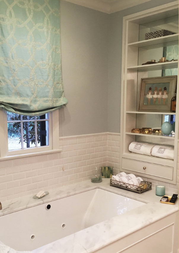 Foto på ett badrum, med ett nedsänkt handfat, luckor med glaspanel, vita skåp, marmorbänkskiva, ett platsbyggt badkar, en dusch i en alkov, vit kakel, keramikplattor, vita väggar och marmorgolv