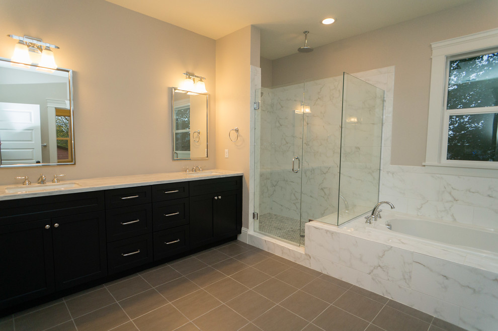 Amerikansk inredning av ett stort en-suite badrum, med ett undermonterad handfat, luckor med infälld panel, svarta skåp, marmorbänkskiva, ett platsbyggt badkar, en dusch i en alkov, grå kakel, stenkakel, beige väggar och klinkergolv i porslin