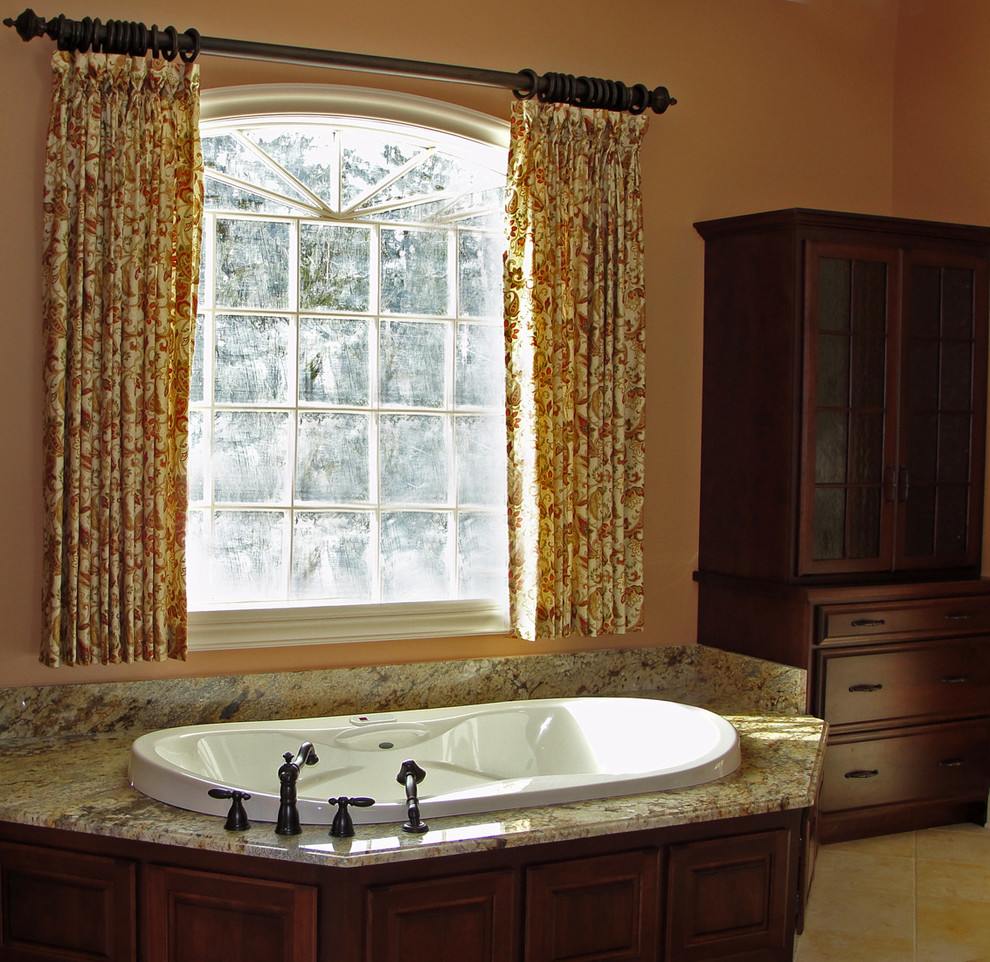 Пример оригинального дизайна: большая главная ванная комната в классическом стиле с фасадами островного типа, темными деревянными фасадами, столешницей из гранита, накладной ванной, оранжевыми стенами, полом из травертина, бежевой плиткой и каменной плиткой