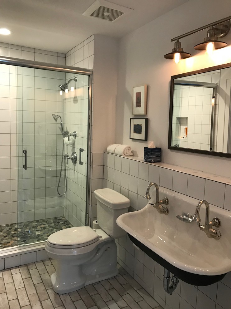 Inredning av ett modernt mellanstort badrum med dusch, med en dusch i en alkov, en toalettstol med separat cisternkåpa, vit kakel, keramikplattor, vita väggar, tegelgolv, ett avlångt handfat, bänkskiva i akrylsten, beiget golv och dusch med skjutdörr