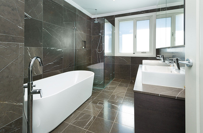 Cette photo montre une salle de bain moderne avec un placard à porte plane, des portes de placard marrons, une douche d'angle, un carrelage noir, un carrelage marron, un carrelage gris, un mur marron, une vasque et une baignoire indépendante.