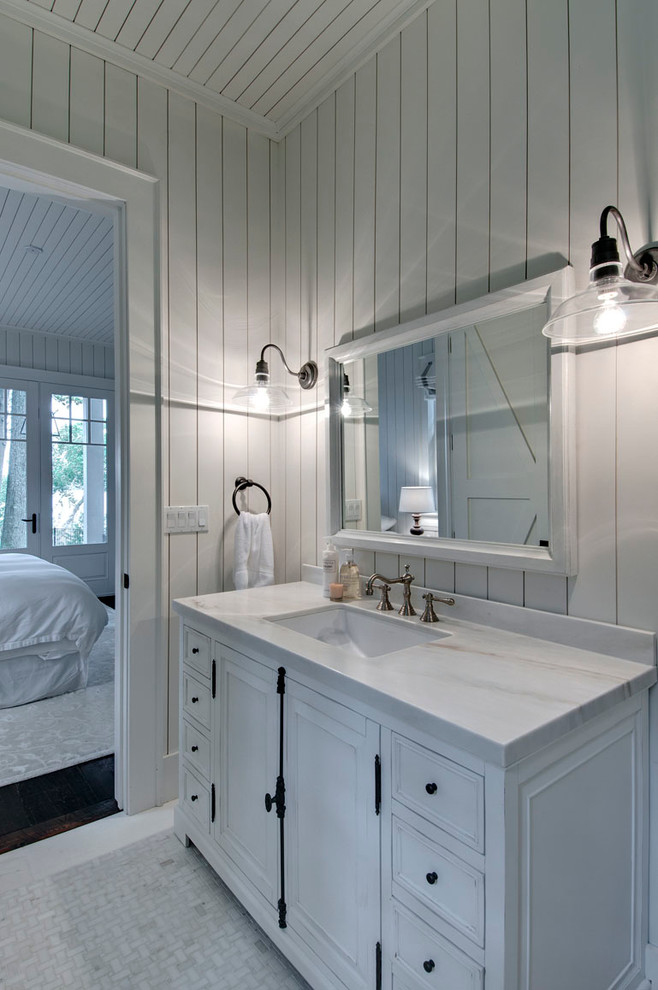 Immagine di una stanza da bagno stile marino con lavabo sottopiano, ante bianche e pavimento con piastrelle a mosaico