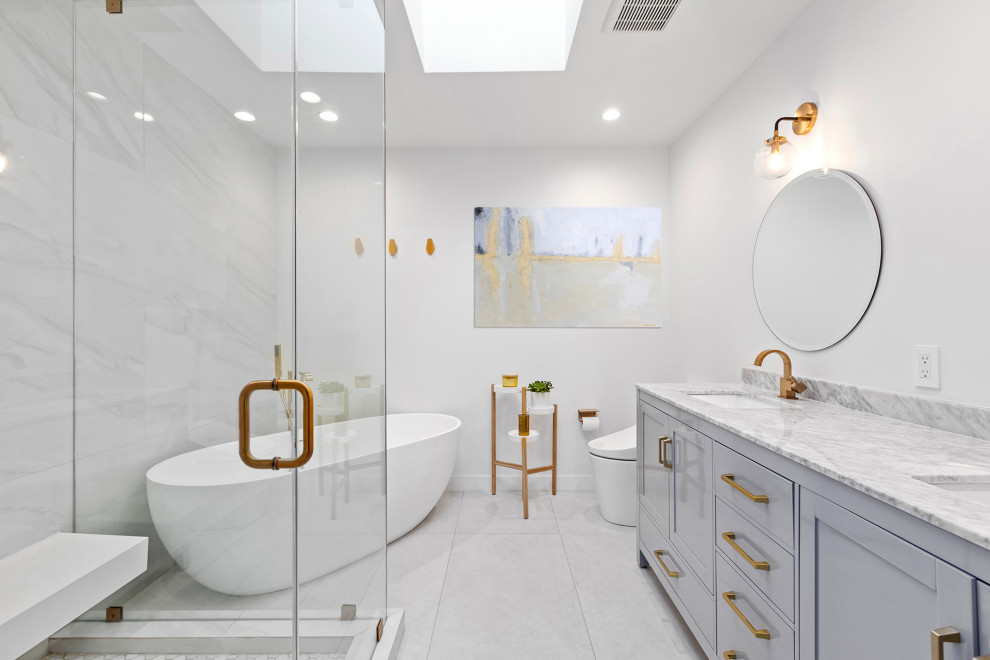 Idées déco pour une salle de bain classique avec un placard à porte shaker, des portes de placard grises, une baignoire indépendante, un mur blanc, un lavabo encastré, un sol gris, un plan de toilette gris, meuble double vasque et meuble-lavabo encastré.